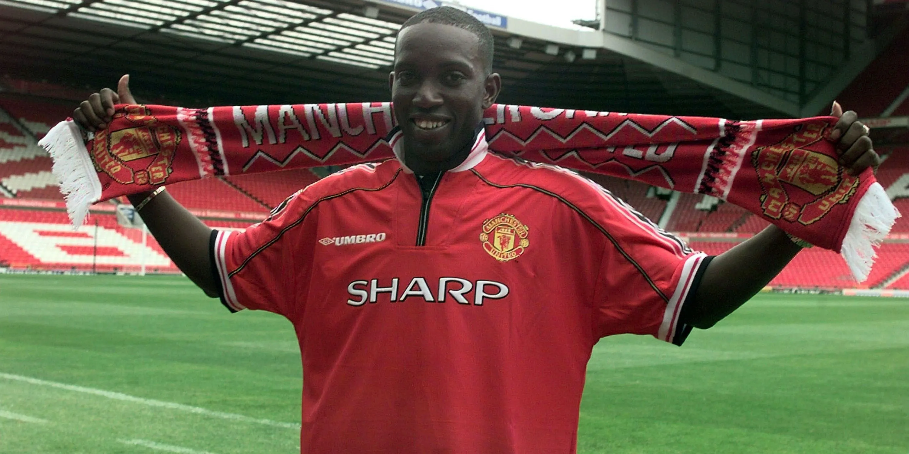 Dwight Yorke giơ cao chiếc khăn Manchester United sau khi ký hợp đồng với câu lạc bộ